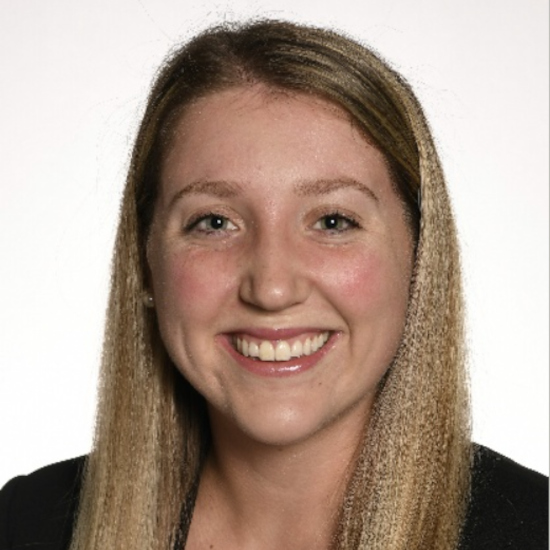 Picture | Austin & Reid Dental Care Close-up portrait of a smiling woman with long blond hair against a white background, wearing a dark top.